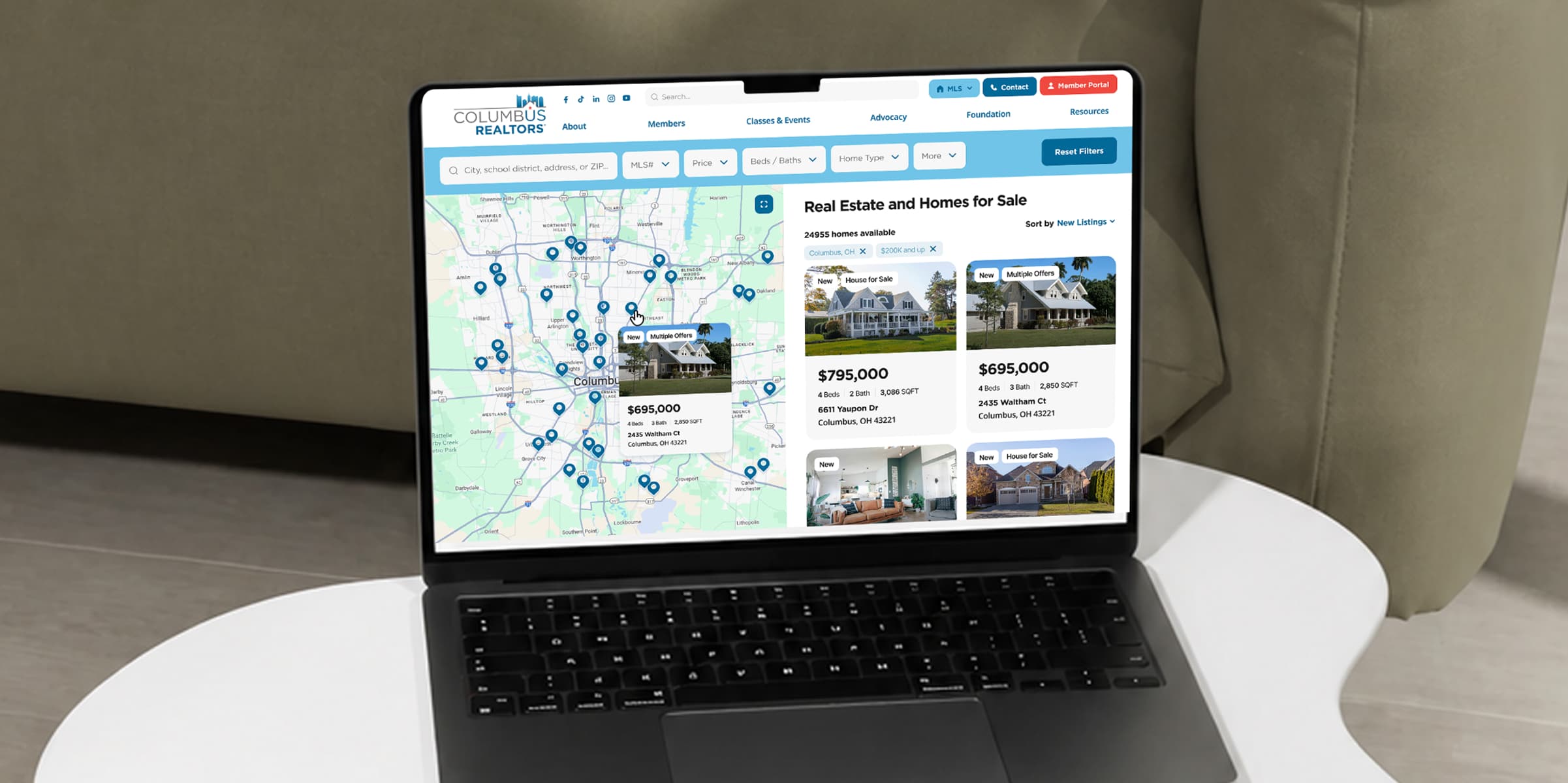Laptop showing the Columbus REALTORS® property search — a map of Columbus with listing pins beside home-for-sale cards